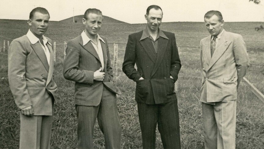 Bronius Srederas stands with three other man in a paddock.