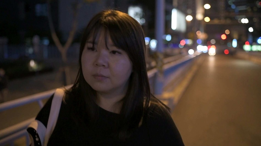 A woman walks down a street at night.