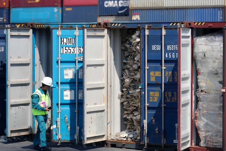 A Malaysian official inspects a container filled with plastic waste