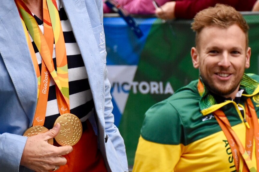 Dylan Alcott looks at Paralympic medals during Melbourne parade