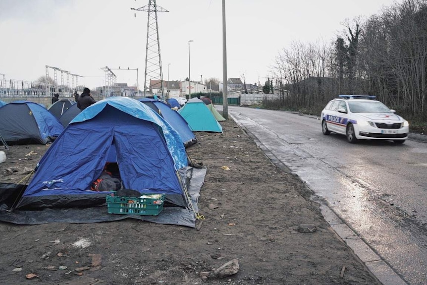 A police car patrols near a migrant camp in Calais.