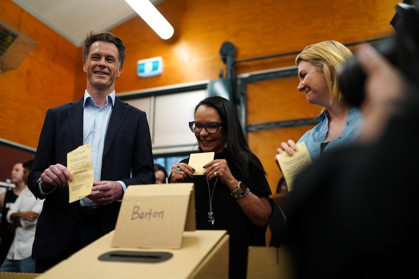Chris Minns and Linda Burney hold voting ballots and stand in front of a poll box