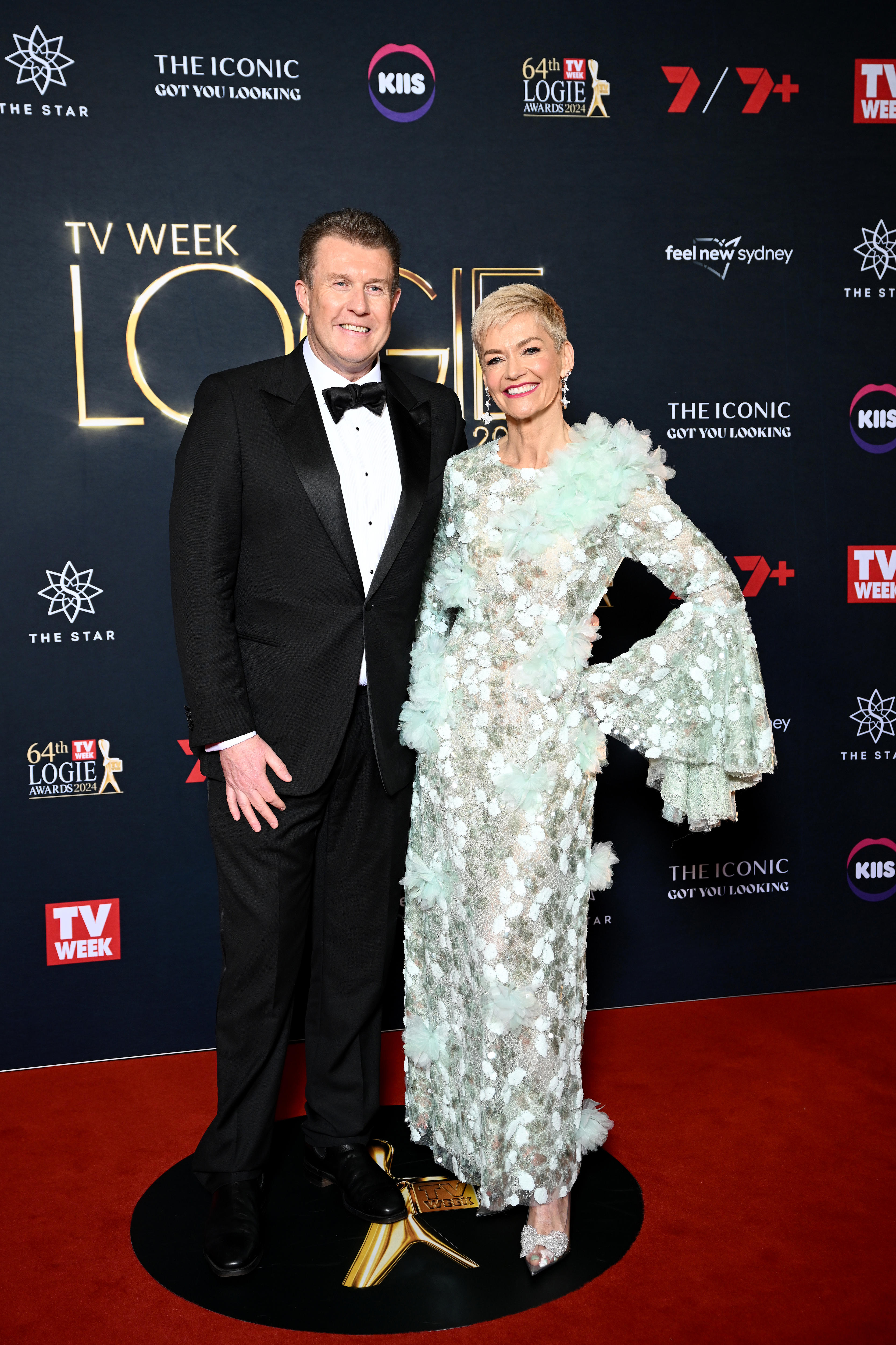 Overton wears a black suit as he stands with Rowe in a pale blue, fluffy long-sleeved gown