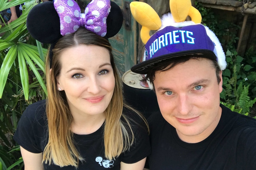 Keira wears Minnie Mouse ears and Matt wears a "hornets' hat with fake antennae on top.