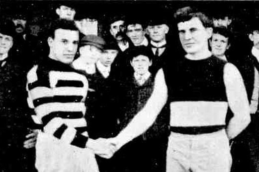 An old, black and white photo of two men in football jerseys shaking hands