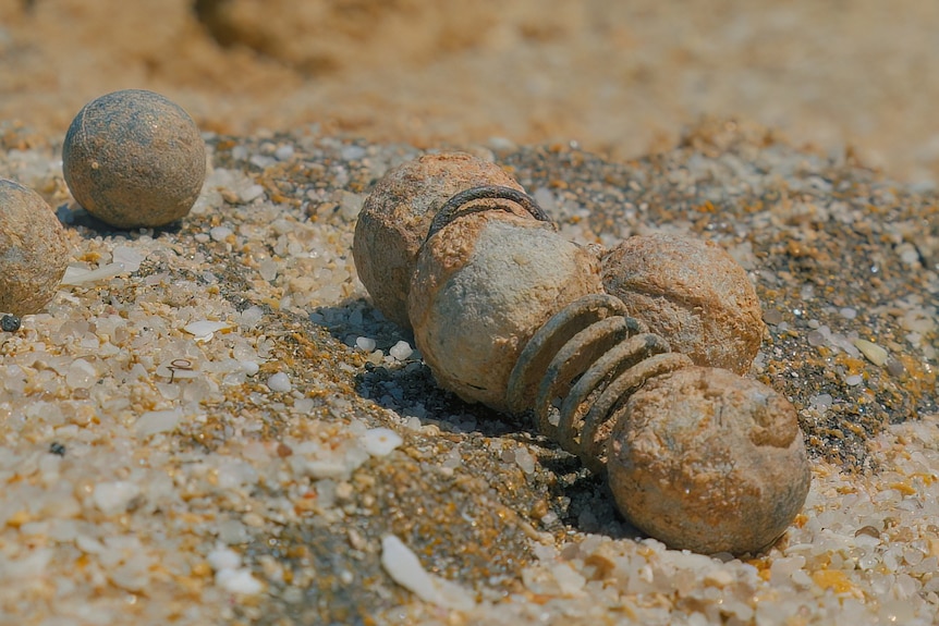 A close up of the musket balls in the sand on the shore