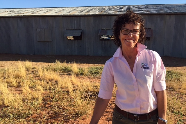 Maureen Scott standing in front of shed in a dry paddock.