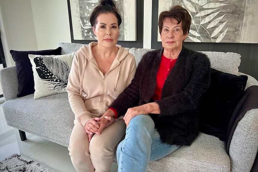 Two ladies sitting on a couch looking upset