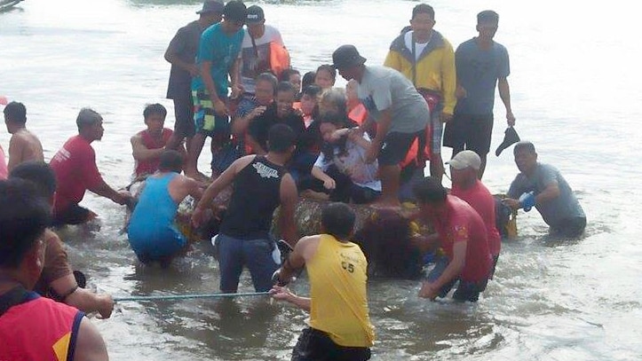 Volunteers pull a rubber boat with rescued passengers from a capsized boat in the Philippines.