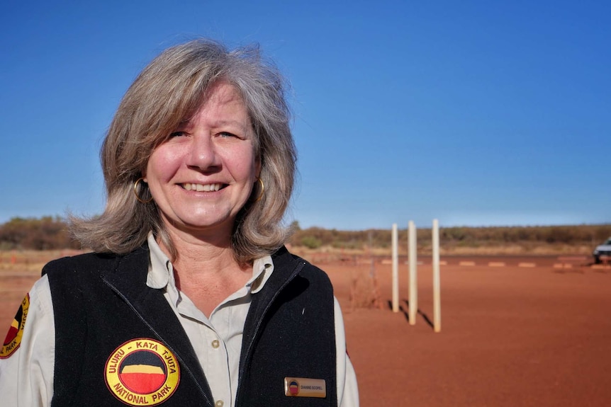 Uluru Park Manager Dianne Scopel smiles at hte camera wearing a black park ranger vest.