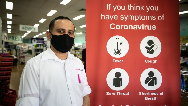 A man in a mask next to a coronavirus sign.