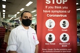A man in a mask next to a coronavirus sign.