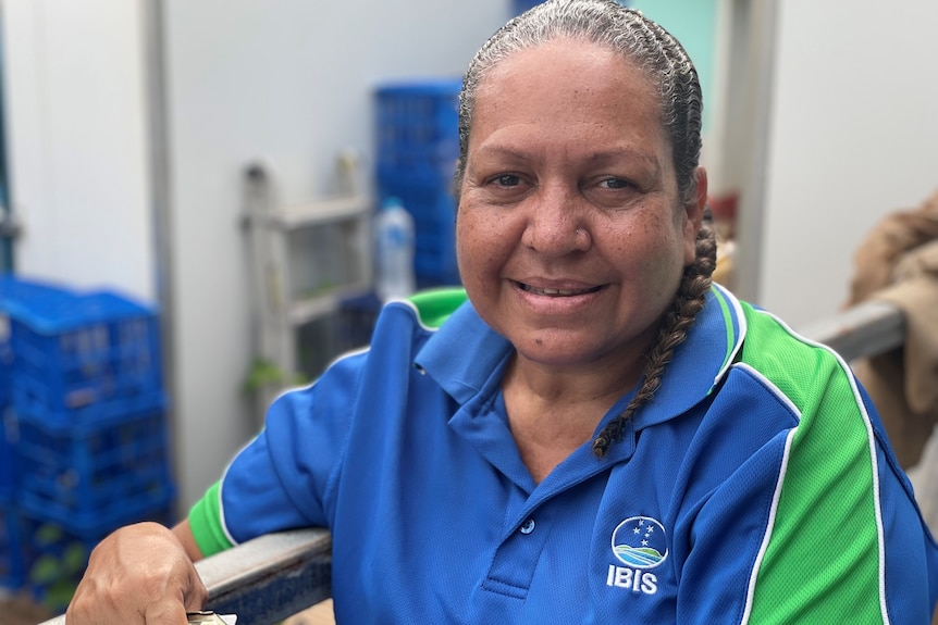 A woman with green and blue shirt smiles at the camera.