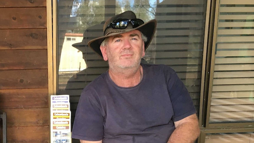 man in a hat sitting on chair on a veranda
