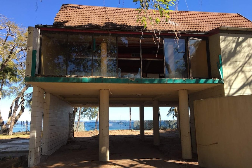 An old and abandoned building with smashed glass windows on a beach.