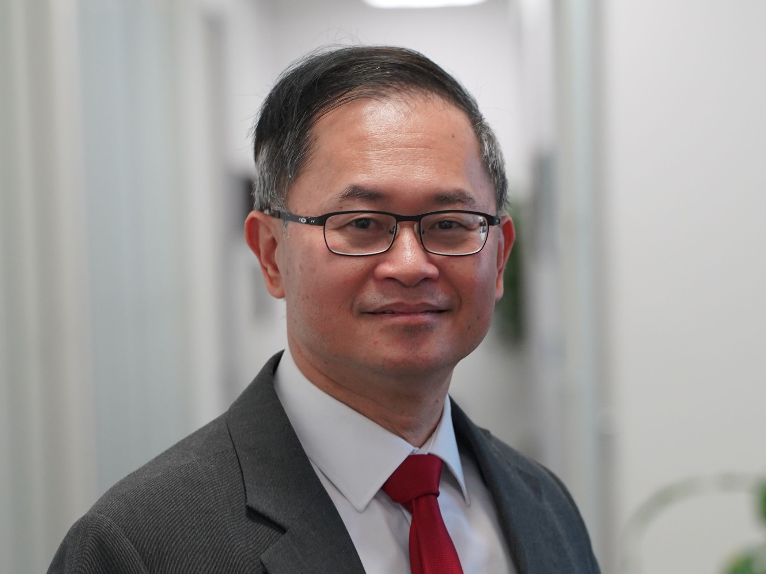 Um homem de óculos sorri para um retrato profissional.