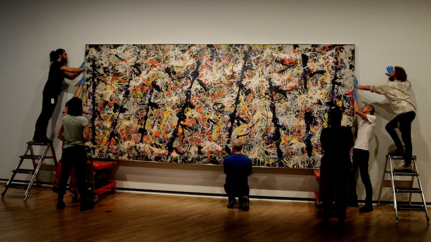 Staff at the National Gallery of Australia rehang Jackson Pollock's Blue Poles artwork.