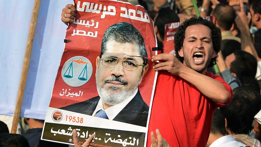 A man holds a portrait of Mohamed Morsi as he takes part in a rally gathering thousands of Islamists in Cairo.