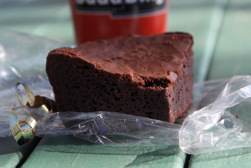 A chocolate brownie and takeaway coffee from Bada Bing, on a picnic table.