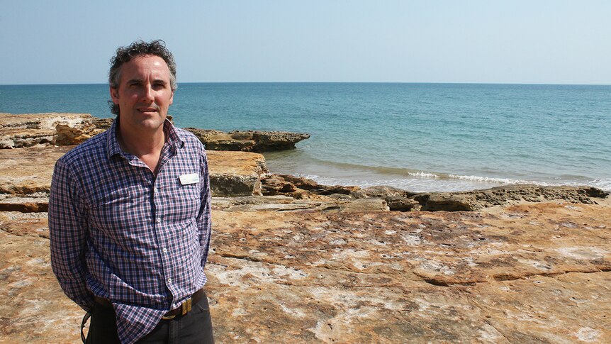 Nik Kleine stands in front of beachside cliffs.
