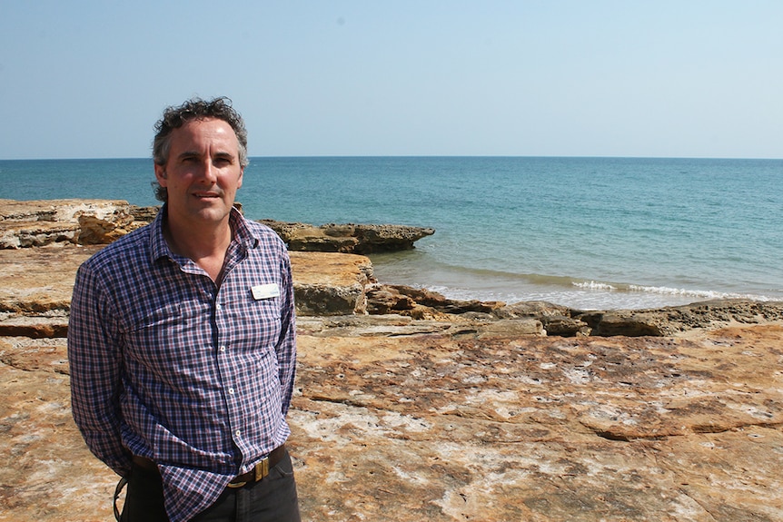 Nik Kleine stands in front of beachside cliffs.