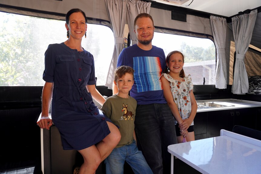 A family of four standing inside their eco-friendly camper.