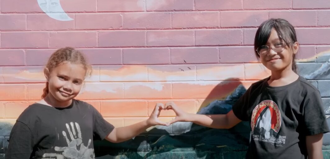 Photo of two children posing their hands together to make a heart