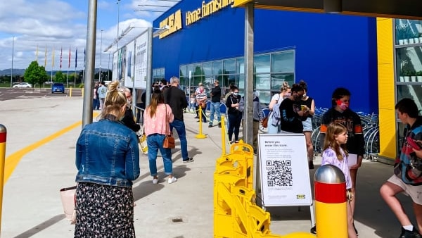 People queue outside the store, wearing masks.