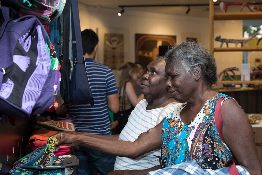 Two people looking at a bag made of Indigenous fabric on the opening night of Provenance Arts.