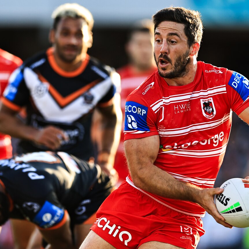 Ben Hunt of the Dragons running and holding the ball in two hands, looking to pass to his right