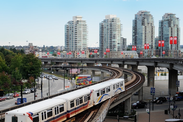 An elevated light rail system going through a big city.