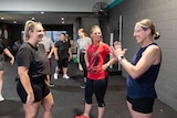 A group of woman who are deaf and hard or hearing stand in a gym having a conversation in Auslan.