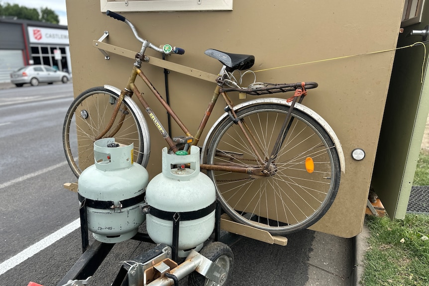 a bicycle and two gas bottles are connected to a tiny home
