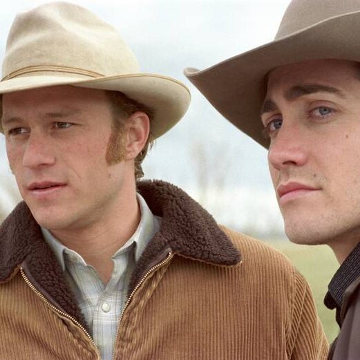 Two men in brown cowboy hats and lumber jackets stare off into the distance.