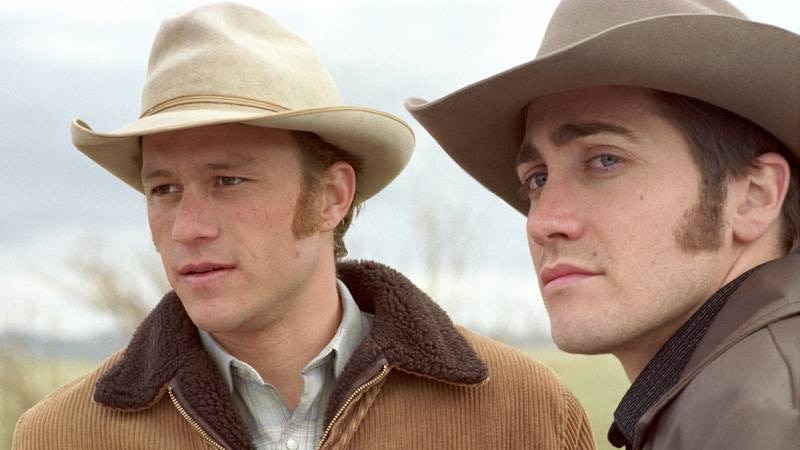 Two men in brown cowboy hats and lumber jackets stare off into the distance.