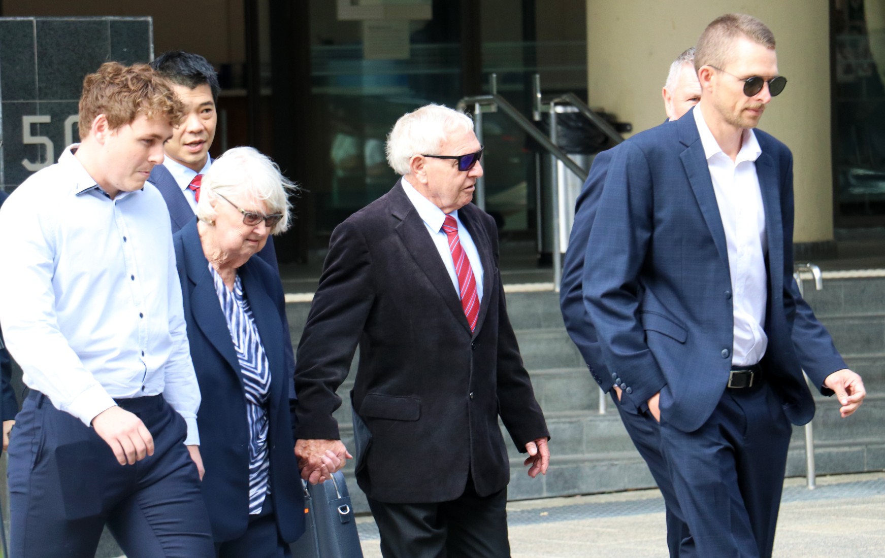 Barry Cable segura a mão de sua esposa e é cercado por apoiadores enquanto sai do tribunal