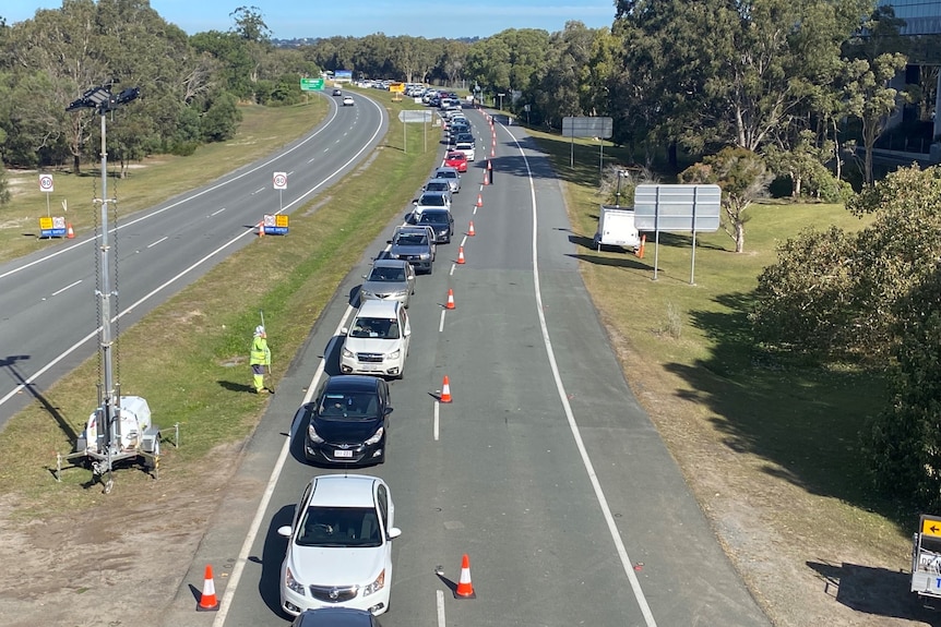 Cars lined up in single line next to traffic cones.