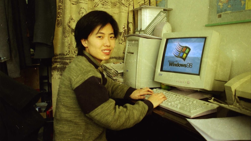 A woman pictured with a computer loading a Windows 98 screen