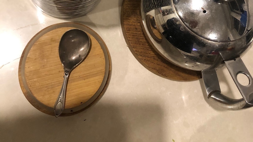 A short stemmed silver spoon shown with teapot and cup.