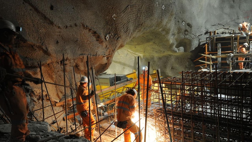 Two men in underground mine using machinery