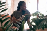 Woman looking at indoor plants for story about how indoor plants are more interesting than they seem