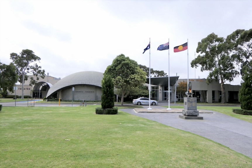 A long 1970a grey building with a sign for council out the front