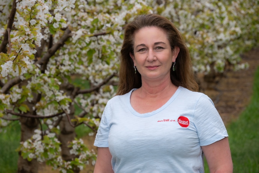 A woman in a white shirt standing in front of some flowering cherry trees