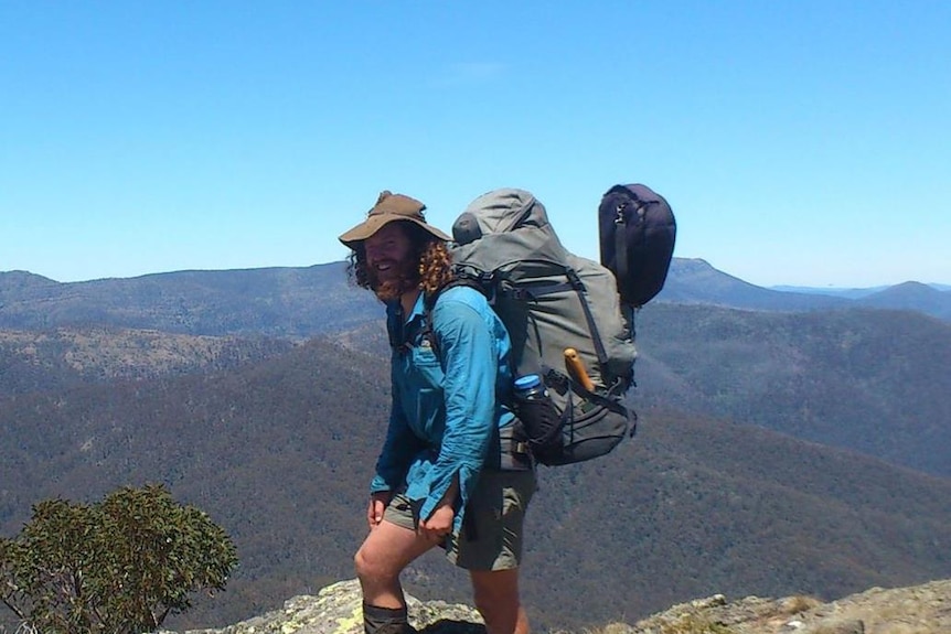 Dan Abikhair hiking in the Victorian high country, pack on his back and mountains in the background