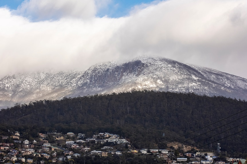 A snow covered mountain viewed from afar. A city is in the foreground