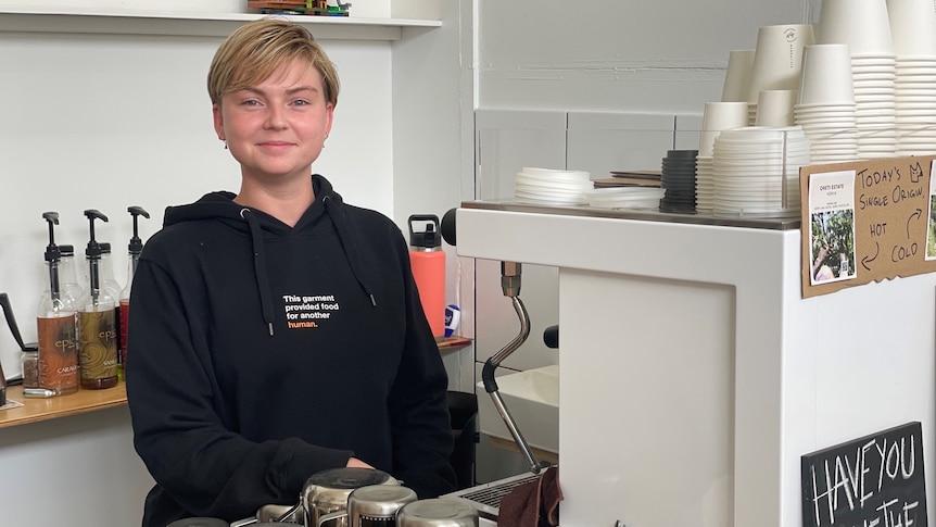 woman stands at coffee machine smiling