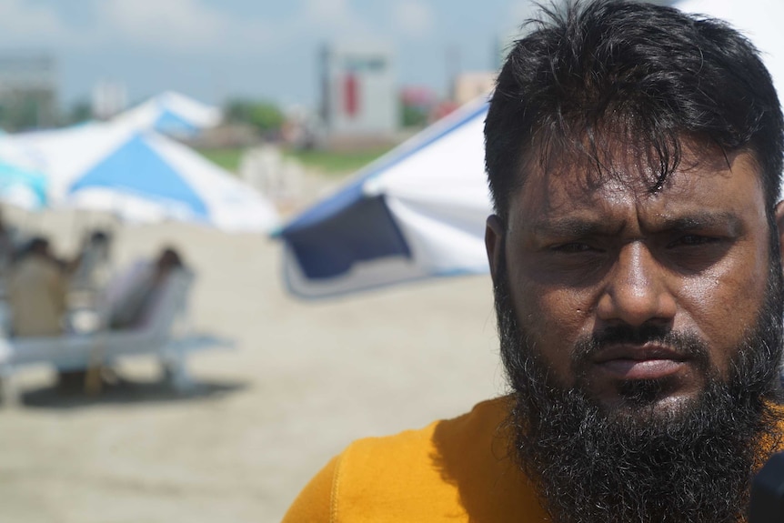 A man stands on a beach looking concerned.