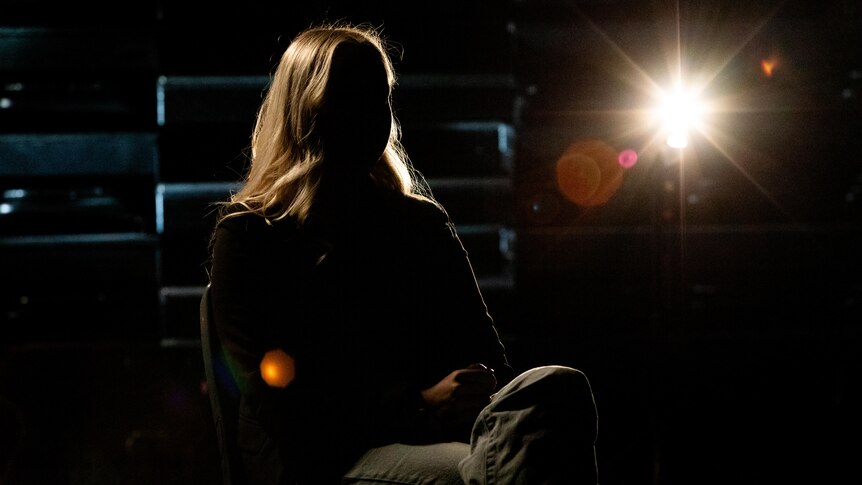 The silhouette of a woman sitting in an auditorium 