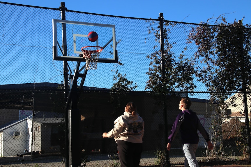 Kids play on an outdoor basketball court