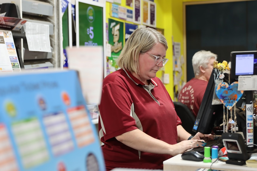 A woman works behind a till in a store